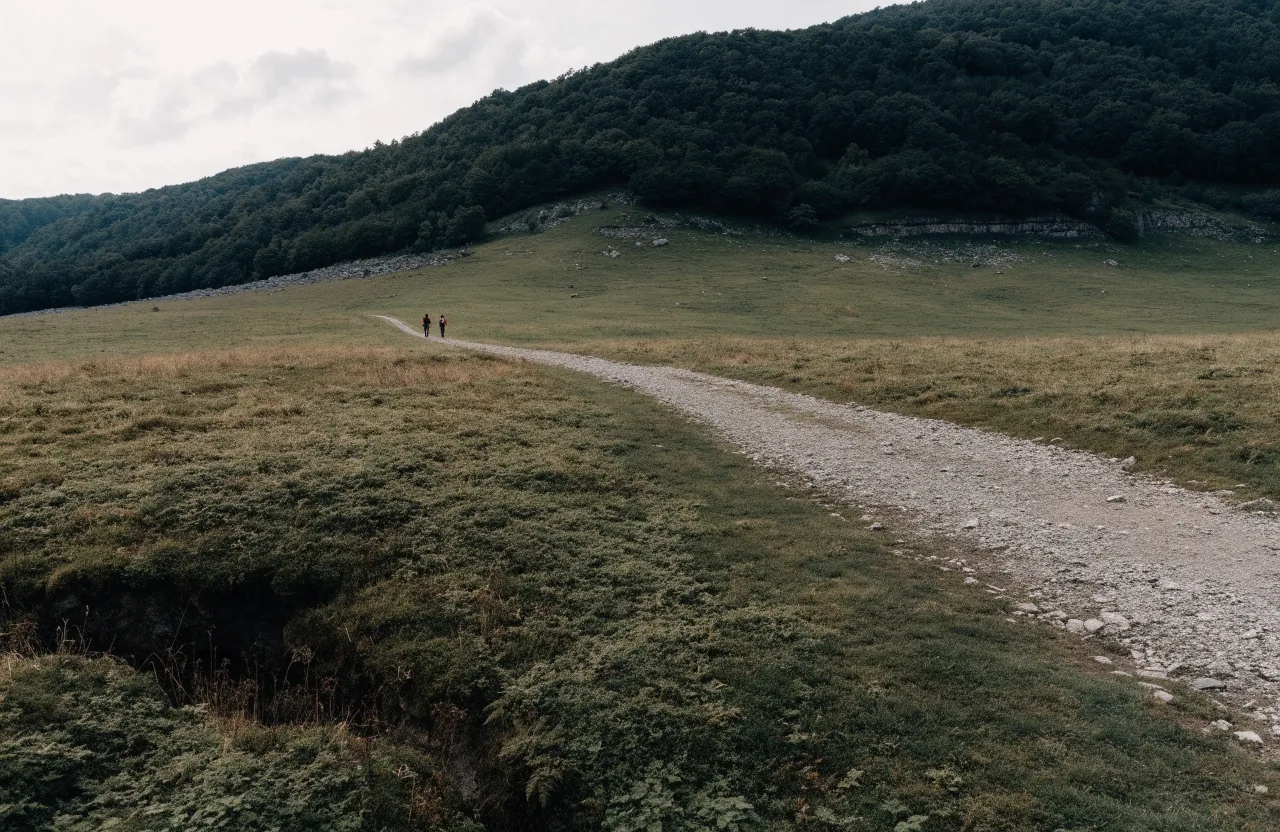 A gravel walking path across Slovenian hill country with walkers far ahead